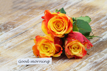 Good morning card with three beautiful colorful roses covered with glitter on wooden surface