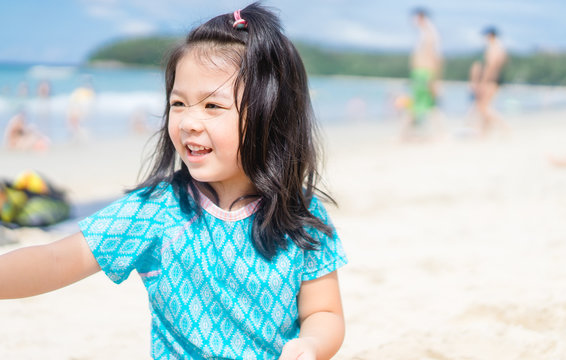 Little asian girl sitting into the sea sand on the beach and play sand castle beach.Vacation and relax concept.Playful active kid on beach in summer vacation.