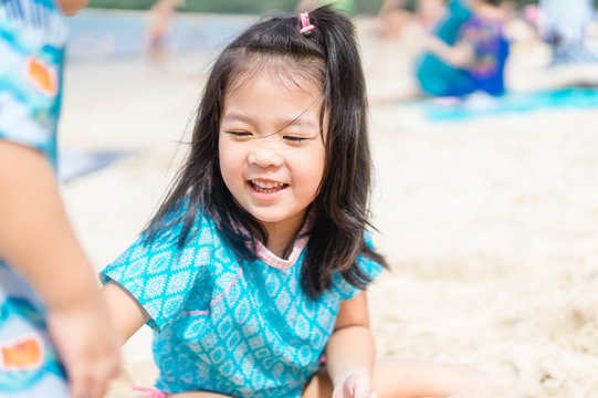 Little asian girl sitting into the sea sand on the beach and play sand castle beach.Vacation and relax concept.Playful active kid on beach in summer vacation.