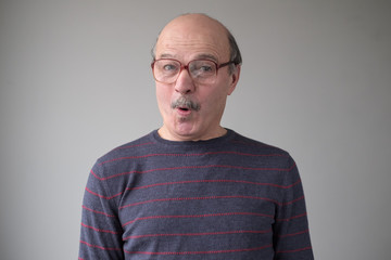 Senior man in huge glasses in being surprised. Wow is it really true. Studio shot. Posititve facial human emotion.