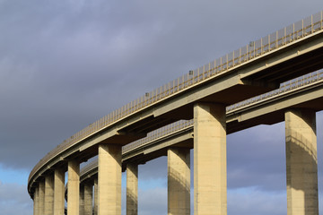 Close-up of a large concrete highway bridge in front of dark clouds in Italy