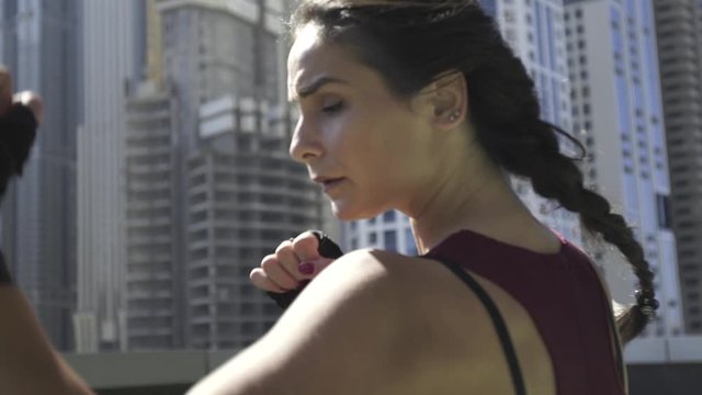 Young sports girl boxing punches on the roof of a building with a city view. Hands in boxing bandages. Close-up. Dynamic camera.