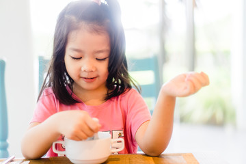 5 years old asian girl eating hong kong congee or rice porridge on breakfast time.Happy time in breakfast with asian food everyday.