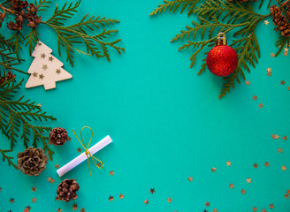Christmas flatlay with green christmas tree branches and red ball on a green background