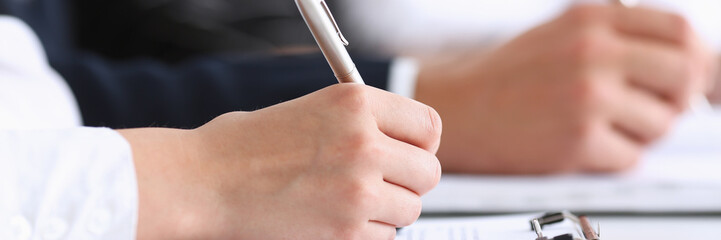 Group of people hold silver pen ready to make