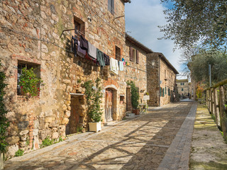 view to old street with shadows and drying clothes in sunshine day in city Monteriggioni in Tuscany in Italy