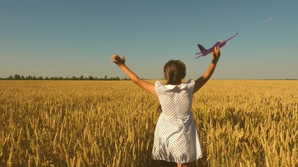 Happy girl runs with a toy airplane on a field in the sunset light. children play toy airplane....