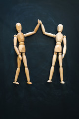 Two wooden people greet each other
