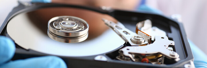 male repairman wearing blue gloves is holding a hard drive
