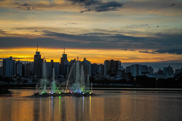 Illuminated fountain flowing at sunset in São José do Rio Preto’s municipal reservoir, creating...
