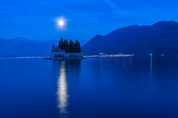 Island of Saint George litted up by the rising Moon. Moon light reflecting at water. Bay of Kotor at blue hour. Cityscape at night, background.