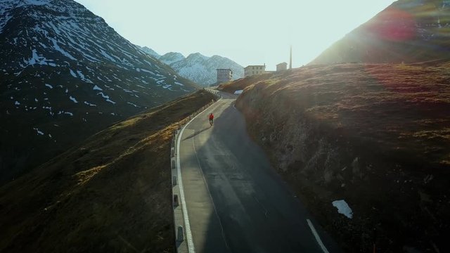 Road cyclist climbs up sunset mountain switchbacks