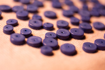 Blue flat disc-like beads on a beige pink knitted woolen background