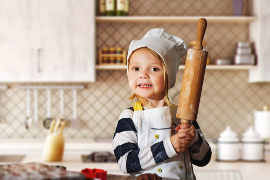 little, sweet girl with rolling pin in the kitchen