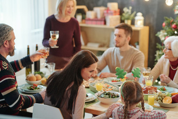 Young mother and her little daughter sitting close to each other by served table