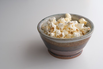 Popcorn in Handmade Potttery Bowl on white background