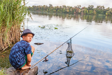 Boy with a fishing rod catches a fish