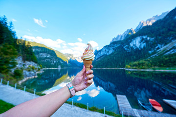Beautiful Gosausee lake landscape with hand and ice cream, Dachstein mountains, forest, clouds and reflections in the water in Austrian Alps © T.Dz