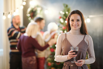Happy young brunette woman with glass of wine congratulating you on Christmas
