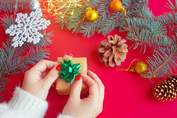 Female's hands holding  gift box with blue ribbon on red background. Christmas, New Year, Valentine's day and birthday concept.