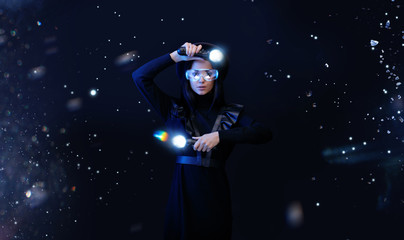 Fototapeta na wymiar Beautiful woman in futuristic black dress over dark magic background. Gamer girl in glasses of virtual reality with controllers in hands. Augmented reality, game, hobby concept. VR. Blue neon light.