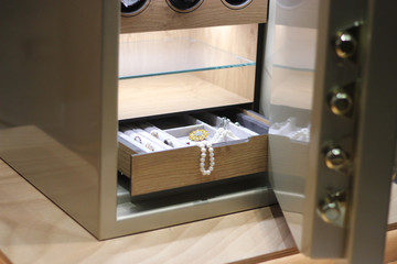 Security metal safe with pearl necklace, diamond jewelry and expensive watches inside