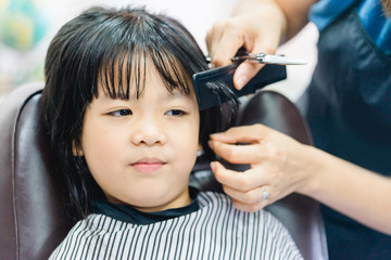 Asian little girl haircut. hairdresser, beauty salon.Cute little asian girl in hairdressing salon.