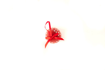 Red christmas ball with white dots and red ribbon on white background, top view