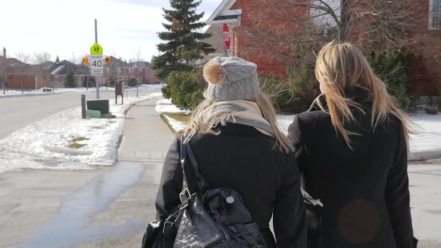 Two Young Females Walking Across The Street Talking In Winter From Behind