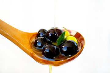 olive branch soaked in olive oil on a wooden spoon isolated on white background
