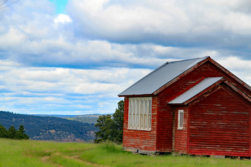 Fototapeta na wymiar Red country house overlooks scenic mountains