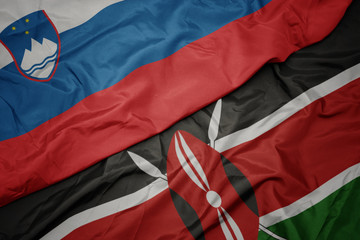 waving colorful flag of kenya and national flag of slovenia.