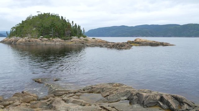 Wide view showing island in the middle of a large body of water surrounded by mountains