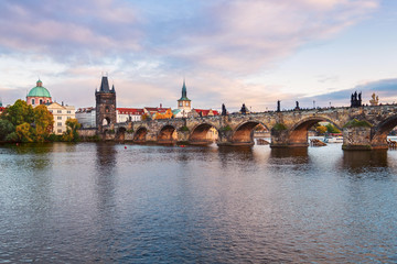 Beautiful view of Old Town buildings and Charles Bridge along the Vltava river at sunset in Prague