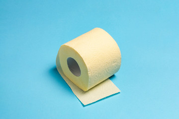 Roll of yellow toilet paper on a blue background. Personal hygiene concept. Flat lay, top view