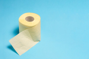 Roll of yellow toilet paper on a blue background. Personal hygiene concept. Flat lay, top view