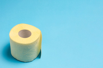 Roll of yellow toilet paper on a blue background. Personal hygiene concept. Flat lay, top view