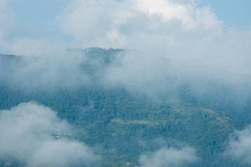 Strong white clouds over a mountain covered by forest. Phewa Lake in Pokhara (Nepal) in the morning.