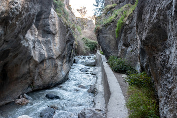 Hiking the Los Cahorros trail through a gorge with a stream near Granada, Spain