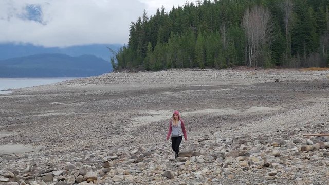 Young Female Walking Along Shoreline Of A Lake in Beautiful British Columbia