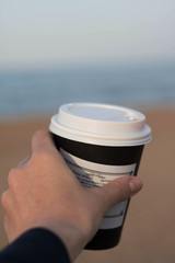 woman holding a cup of coffee on beach