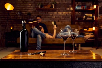 Glasses of red wine on table at home with couple