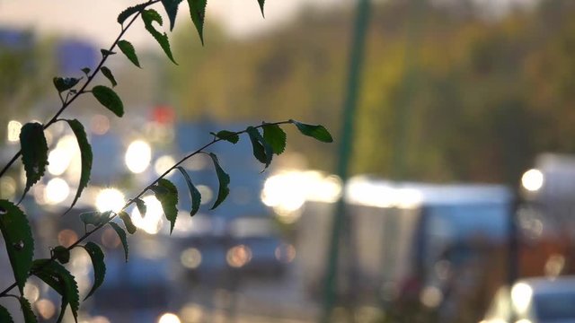The traffik of blurred cars on the highway at rush hour against the background of the city and the radio tower with sun flare in the morning sun..