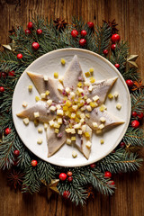 Christmas Herrings fillets with apples, pickled cucumbers, red onion and spices on a ceramic plate...