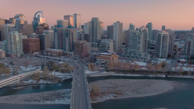 Aerial: Establishing shot of the Calgary city skyline and Bow River at sunset. 