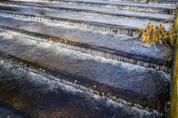 Water pours down the stairs in the river. Cascading waterfall. System for stopping the flow of water.