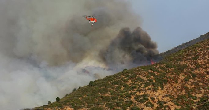 November 9, 2019. Warner Brothers nearby wildfire. Los Angeles county. Red fire service helicopter in a completely smokey sky. Extinguishing a major fire in the Hollywood Hills. 4K