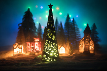 New Year miniature house in the snow at night with fir tree.