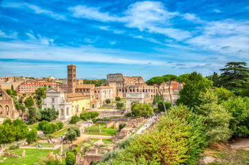Fototapeta na wymiar Aerial panoramic cityscape view of the Roman Forum and Roman Colosseum in Rome, Italy. World famous landmarks in Italy during summer sunny day.