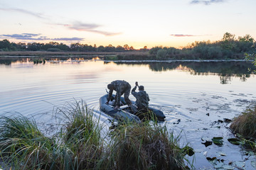 Hunters in a boat swim in a pond in search of wild ducks